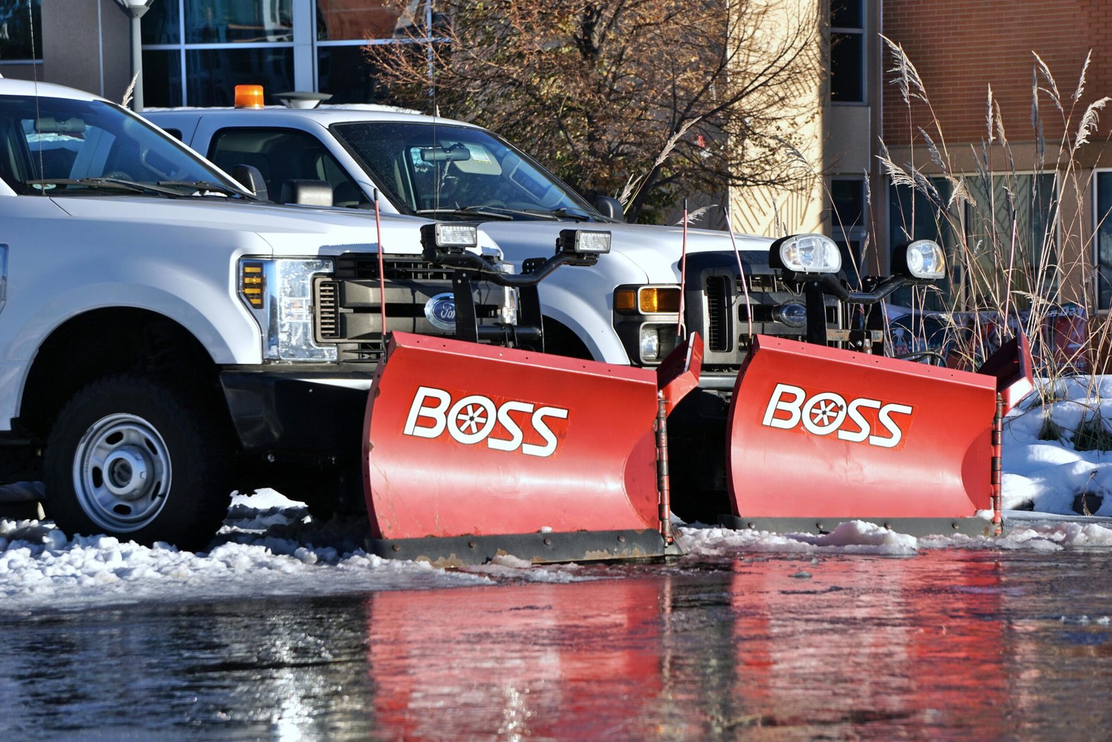 White pickup trucks with red snow plows, poised for winter road clearing.Residential snow removal london ontario